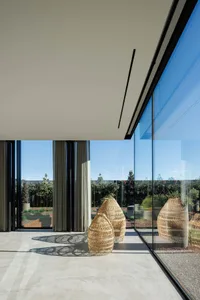 A modern living room with large glass walls and wicker planters.