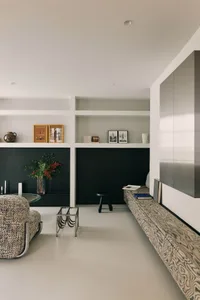 A modern living room with black walls, minimalist decor, and a wooden bench.