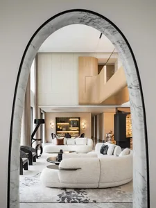 Modern living room with white sofas, minimalist decor, and a geometric archway
