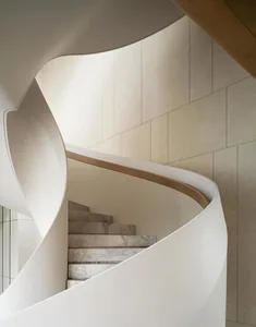 A beautifully curved, modern marble staircase with a white handrail.