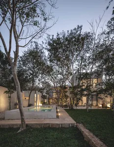 A modern minimalist residential exterior featuring concrete and glass materials surrounded by trees.