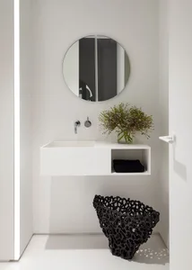 Modern minimalist bathroom with white concrete floating vanity, round circular mirror, and black textured vase beneath floati