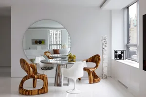 A modern dining room featuring unique wooden chairs and a sleek glass table.