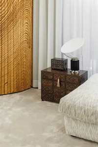 A modern interior design featuring a wooden side table with intricate inlay patterns, a sleek table lamp, and a comfortable u