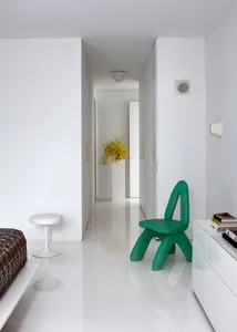 Modern living room with a green chair and white furniture.