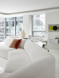 Modern, minimalist living room featuring a white fabric couch with a red throw pillow.