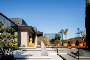 A modern house with a concrete exterior and a glass wall next to a swimming pool.