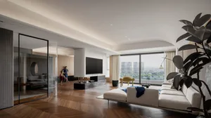 A modern living room with wooden flooring, white furniture, and large windows overlooking a cityscape.
