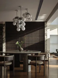 Modern dining room with marble elements, featuring a round table, chairs, and a chandelier.