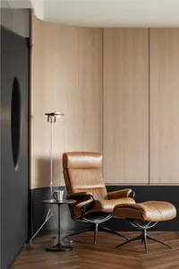 A modern lounge area featuring a brown leather recliner, wooden panels, and floor lamp.