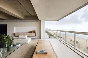 A minimalist living room with a view of the ocean, featuring modern furniture and natural light.