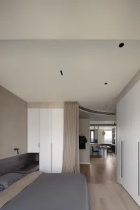 A modern bedroom with a minimalist design, featuring neutral colors and integrated storage solutions.