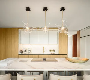 Modern kitchen with marble countertops, wood accents, and pendant lighting.