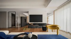 Modern living room featuring a mix of wood and other materials, with a large television screen and contemporary furniture.