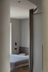 Modern minimalist bedroom with fabric bed and light walls and floor.