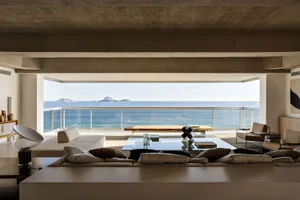 Sofa adorned with plush pillows and a glass-topped table overlooking the ocean from a contemporary residential interior.