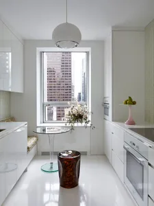 A modern kitchen with white cabinets and a window overlooking a cityscape.