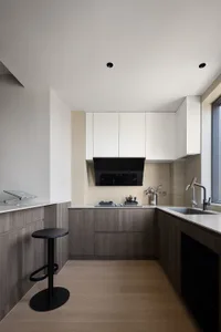 A modern minimalist kitchen featuring wood elements and a clean, white aesthetic.