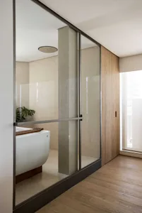 Modern bathroom featuring glass walls and wooden accents