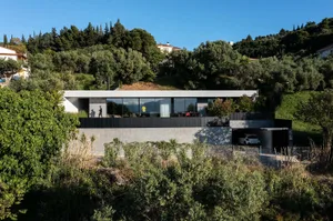 A modern house with a minimalist design, featuring a combination of concrete and glass materials.