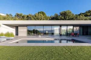 A modern house with a concrete exterior, featuring large glass windows and a swimming pool surrounded by green grass.