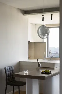 A modern kitchen with wood countertops, leather chairs, and marble backsplash.