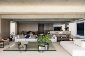 Modern living room with minimalist design, concrete walls, wooden floor, and glass furniture.