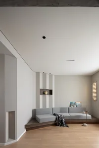 A modern living room with a gray sofa, wooden floor, and built-in seating area.