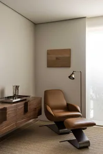 Modern living room with a brown leather armchair and metallic floor lamp, featuring a geometric wall art.