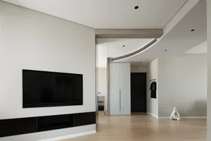 A modern living room with light wooden flooring, white walls, and a minimalist design.