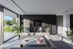 A modern minimalist living room featuring a concrete floor, glass wall, and wooden furniture.