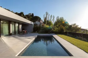 A modern residential home with a concrete pocket pool surrounded by a well-manicured garden.