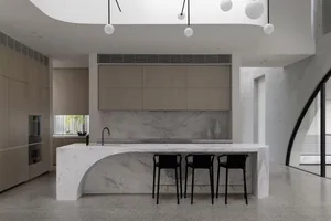 Modern kitchen with a marble countertop and black bar stools.