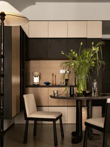 A modern, minimalist kitchen interior with wooden cabinets and a round dining table.