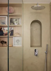 A minimalist bathroom with concrete walls and shelves containing various artworks and seashells.