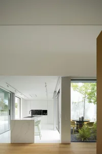Modern, minimalist style kitchen featuring white marble countertops and white cabinets.