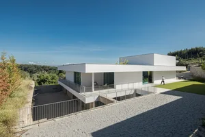Modern residential house with white concrete and stone exterior, featuring a clean, minimalist design.