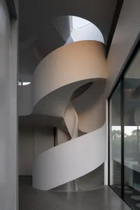 Modern interior design featuring a concrete spiral staircase with natural light.