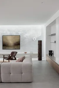 A modern interior design of a living room featuring a concrete wall, minimalist furniture, and abstract art.
