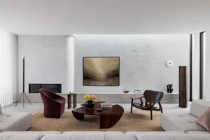 A modern living room featuring concrete, wood, and fabric materials, with a comfortable seating area, a coffee table, and dec