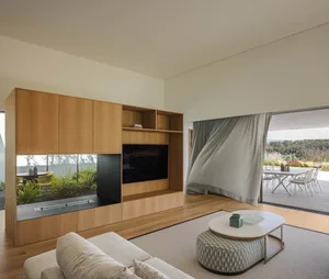 Modern living room featuring sleek, compact wooden storage units and a white ottoman on a large rug.