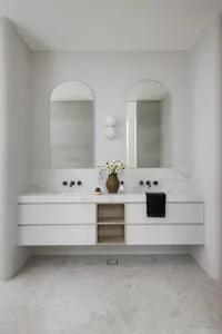 Modern minimalist bathroom with marble finishes, white fixtures, and a floating vanity with double sinks.