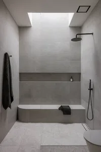 Modern minimalist bathroom with concrete walls, large skylight, and built-in bench with a towel hanging nearby.