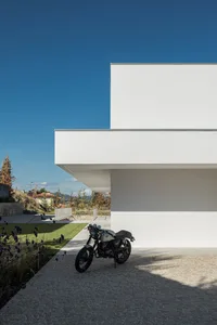 A modern minimalist house with a white exterior made of concrete.