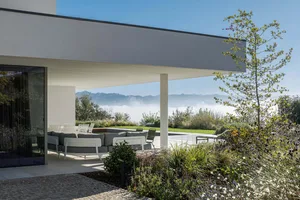 Modern minimalist residential exterior featuring concrete and glass materials.