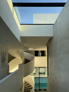 現代簡約室內空間，設有混凝土與玻璃材質的螺旋樓梯，可眺望游泳池景觀。