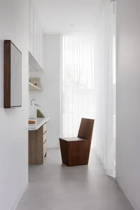 Modern residential interior featuring a wooden chair, a glass wall, and concrete flooring.