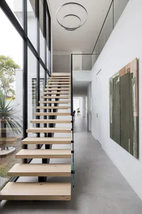 Modern, wooden staircase with glass railing in a contemporary interior design setting.