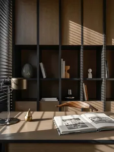 A minimalist home office library with a wooden desk, metal chair, and bookshelf.