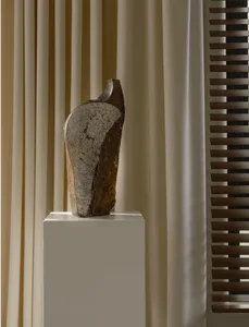 A minimalist stone sculpture on a pedestal in a modern interior setting
